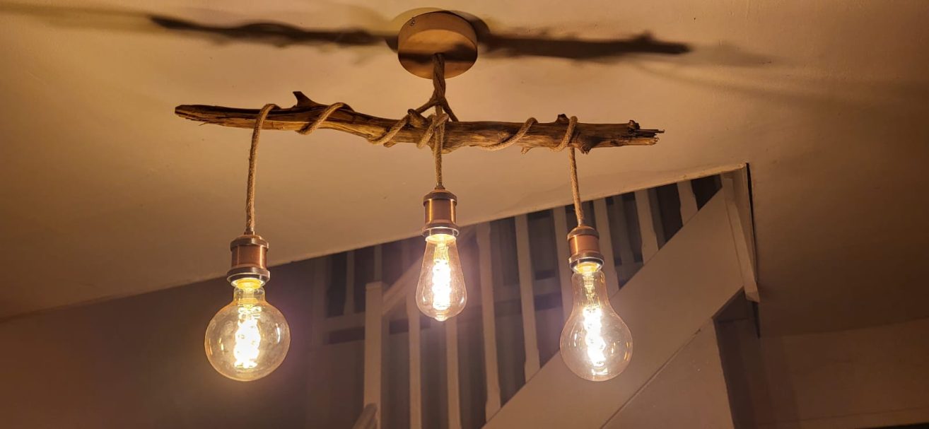 Suspension lumineuse en bois flotté avec trois ampoules suspendues.